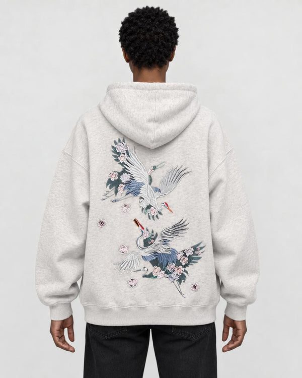 Model wearing the oatmeal crane embroidered hoodie with black jeans, back view