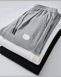 Folded gray, white and black waffle knit joggers showing the drawcord and patch label