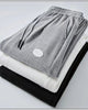 Folded gray, white and black waffle knit joggers showing the drawcord and patch label