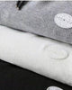 Close-up of the waffle texture and round patch label on the gray and white joggers