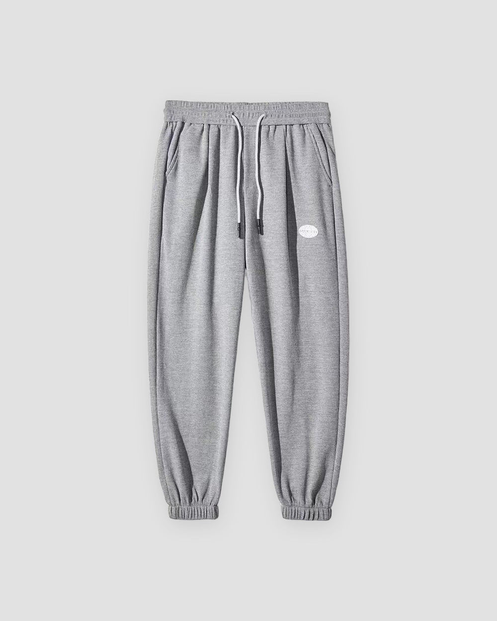 Gray waffle knit joggers with a white drawcord and ribbed ankle cuffs, front view