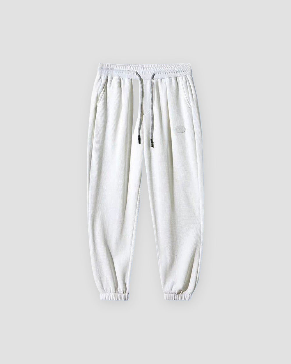 White waffle knit joggers with a white drawcord and ribbed ankle cuffs, front view