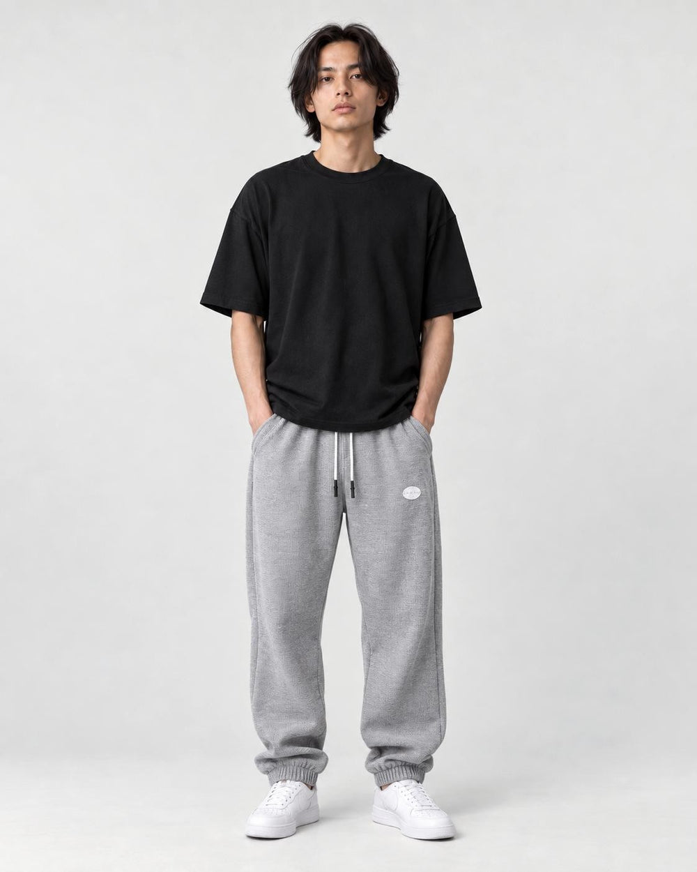 Model wearing the gray waffle knit joggers with a black tee, front view