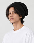 Model wearing the black waffle knit beanie pushed back, three-quarter view