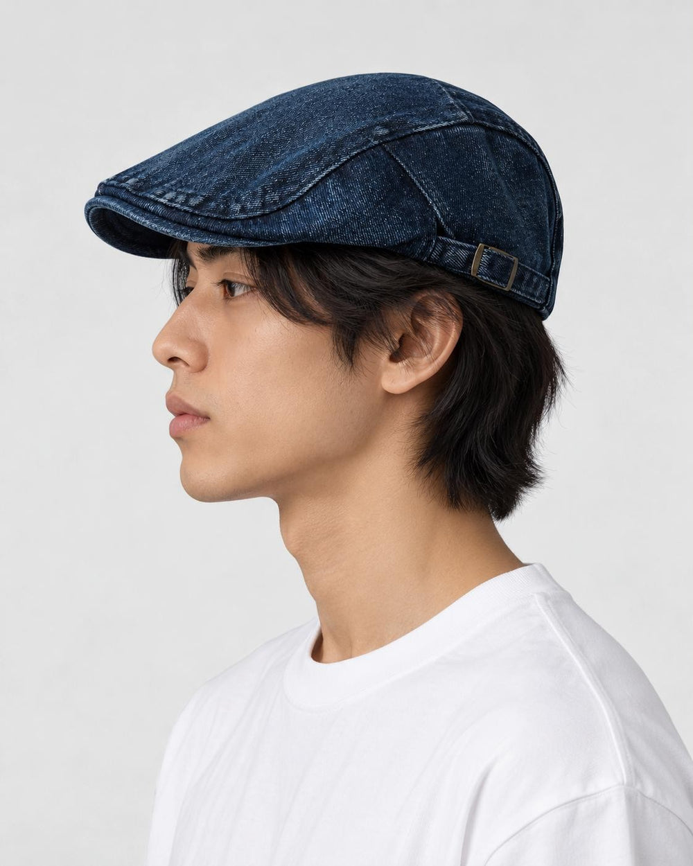 Model wearing the dark blue denim flat cap, side view showing the back strap
