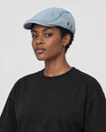 Model wearing the light blue washed denim flat cap, three-quarter view