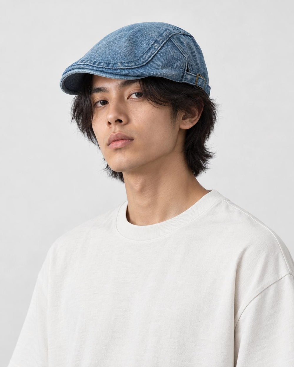 Model wearing the medium blue denim flat cap, three-quarter view