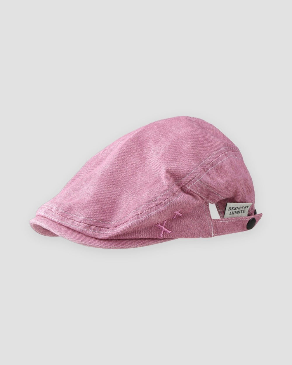 Pink washed flat cap with a short peak, cross stitches and a white woven tab