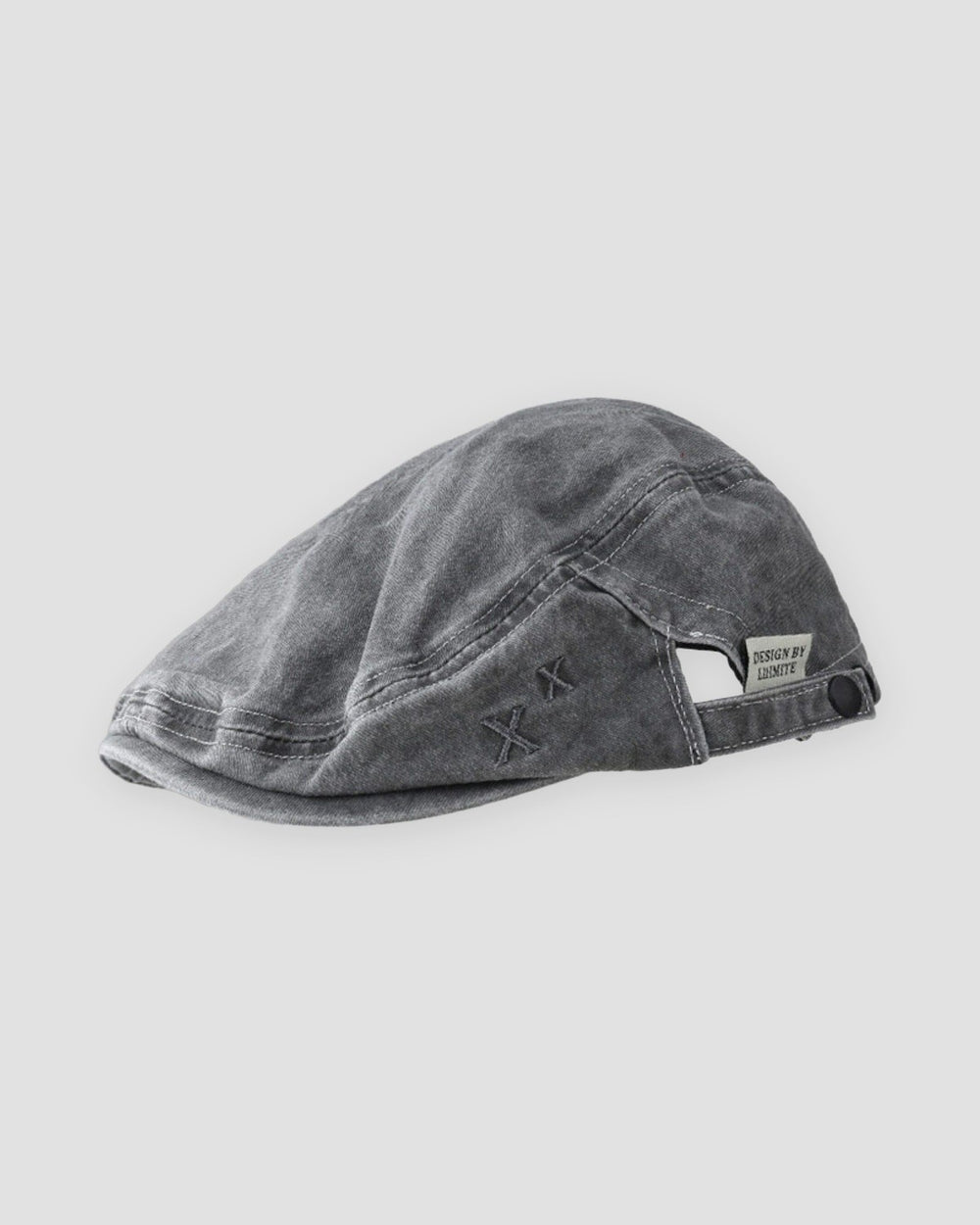 Washed black flat cap with a short peak, cross stitches and a white woven tab