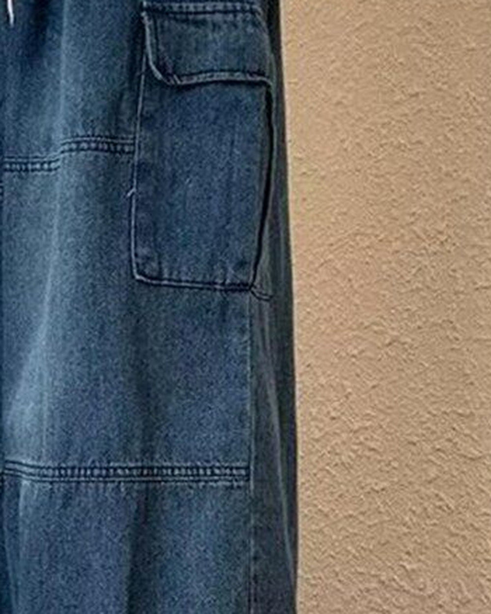 Close-up of the flap cargo pocket and panel seam on the blue denim