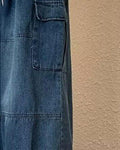 Close-up of the flap cargo pocket and panel seam on the blue denim