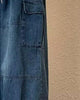 Close-up of the flap cargo pocket and panel seam on the blue denim