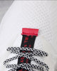 Close-up of the white knit, red pull tab and speckled round laces