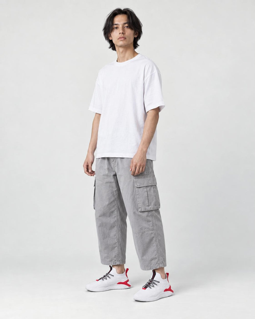 Model wearing the white knit sock sneakers with cropped gray cargo pants