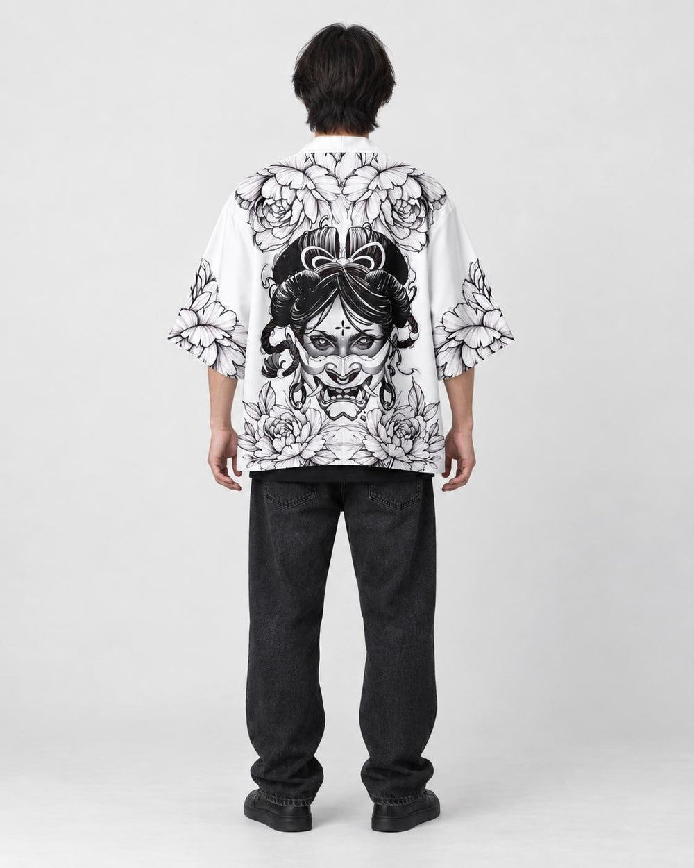 Full-length back view of a man in the white haori with a black line-art demon mask and peonies, black tee and black jeans