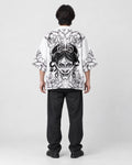 Full-length back view of a man in the white haori with a black line-art demon mask and peonies, black tee and black jeans