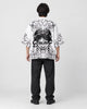Full-length back view of a man in the white haori with a black line-art demon mask and peonies, black tee and black jeans