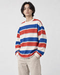 Model wearing the red striped sweatshirt with stone trousers, three-quarter view