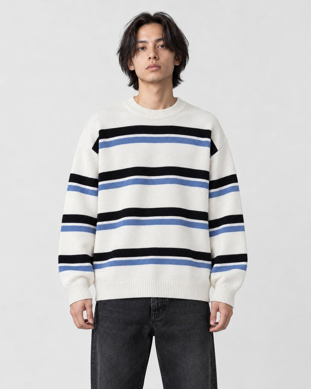 Model wearing the white striped knit sweater with dark jeans, front view