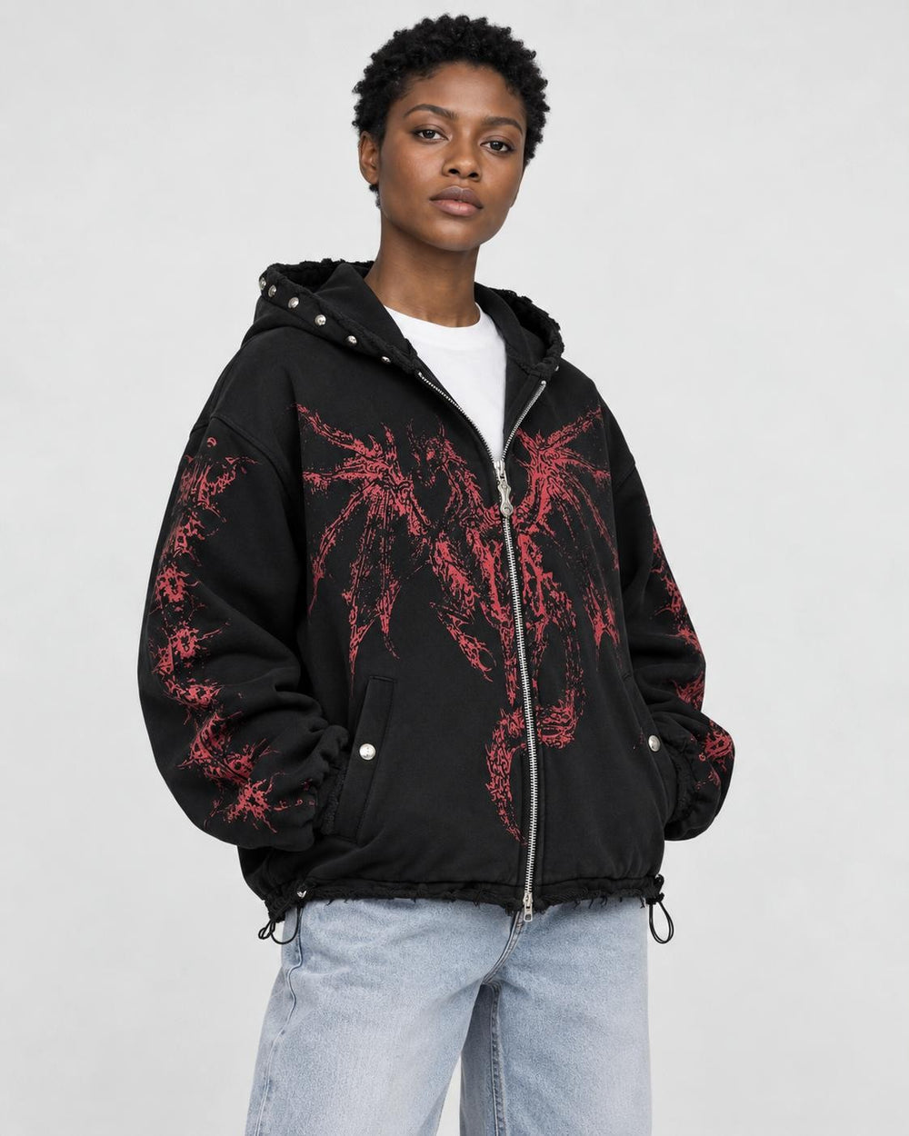 Model wearing the black zip hoodie with a red winged dragon graphic, three-quarter view