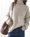 Woman in the beige woven sweater with a brown shoulder bag, the ribbed cuff resting at her jeans pocket