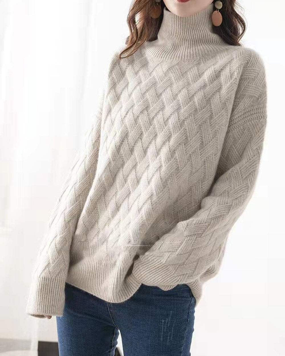 Beige basket-weave sweater worn loose with a hand in the jeans pocket, ribbed hem showing