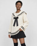 Woman in the cream sailor-collar cable-knit sweater and black skirt, three-quarter view