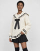 Woman in the cream sailor-collar cable-knit sweater and black skirt, three-quarter view