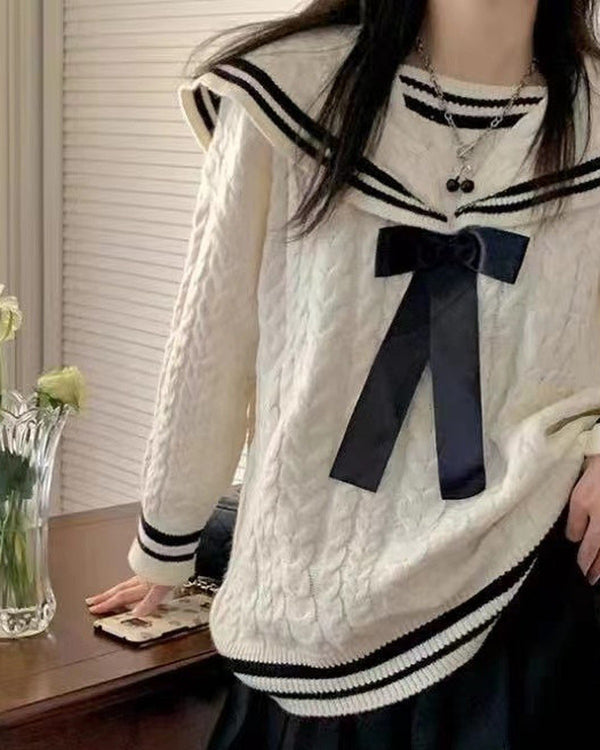 Cream cable-knit sweater with a striped sailor collar and a black ribbon bow, torso view