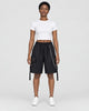 Woman in black knee-length cargo shorts with a silver chain and side straps, a white cropped tee and white sneakers