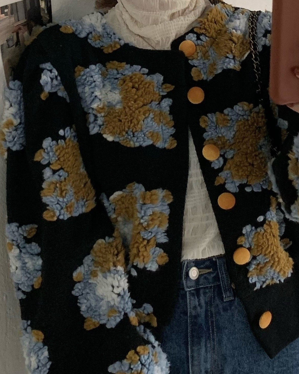 Close view of the raised flower patches and gold buttons on the black jacket