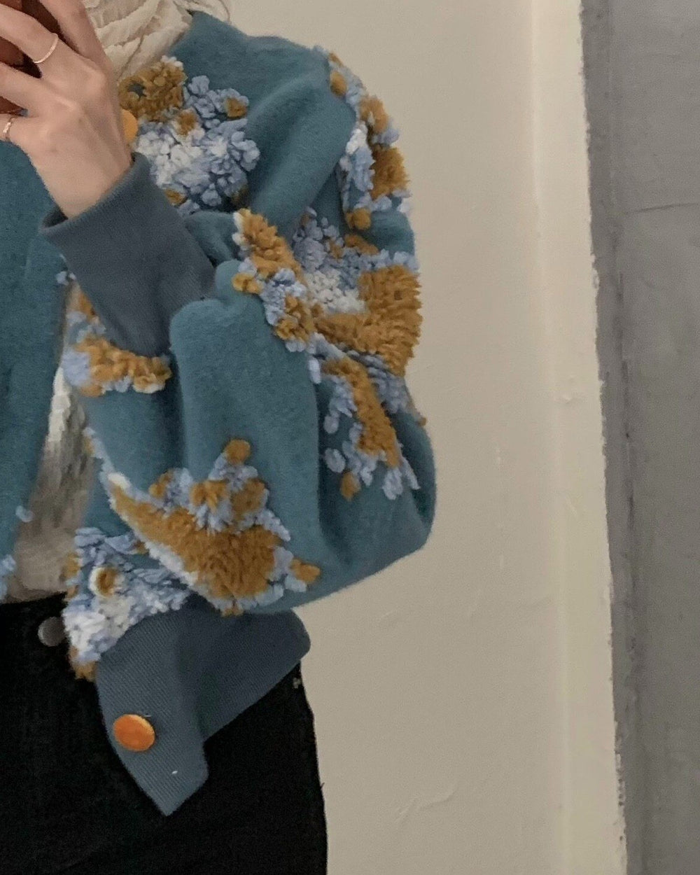 Close view of the raised yellow and pale blue flower patches on the teal jacket
