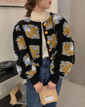 Woman in the black cropped jacket with raised yellow and pale blue flower patches and gold buttons