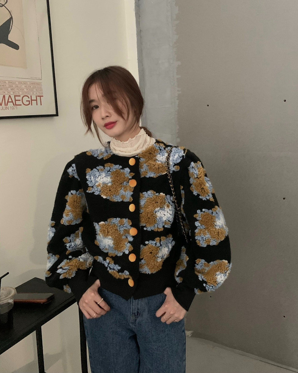 Woman standing in the black flower-patch jacket with a phone in her hand
