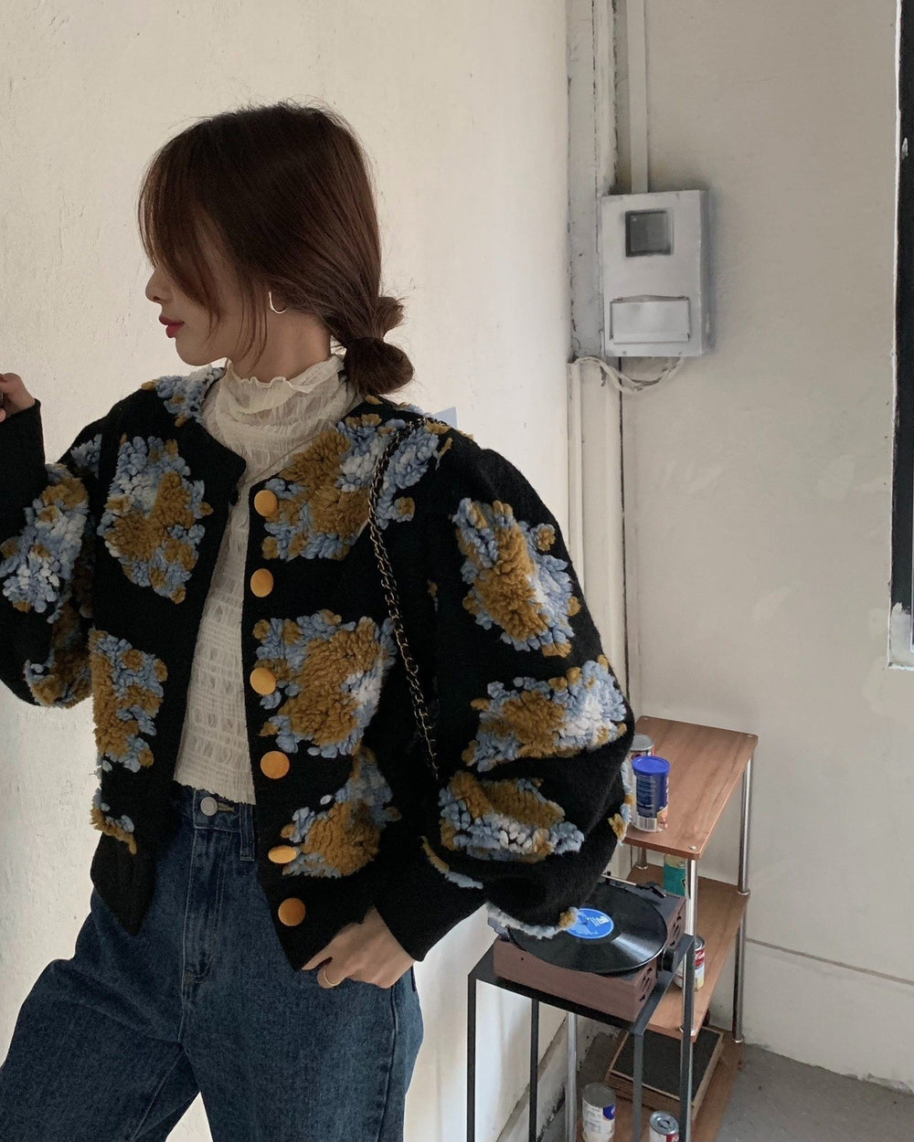 Woman in the black flower-patch jacket with a hand raised to take a photo