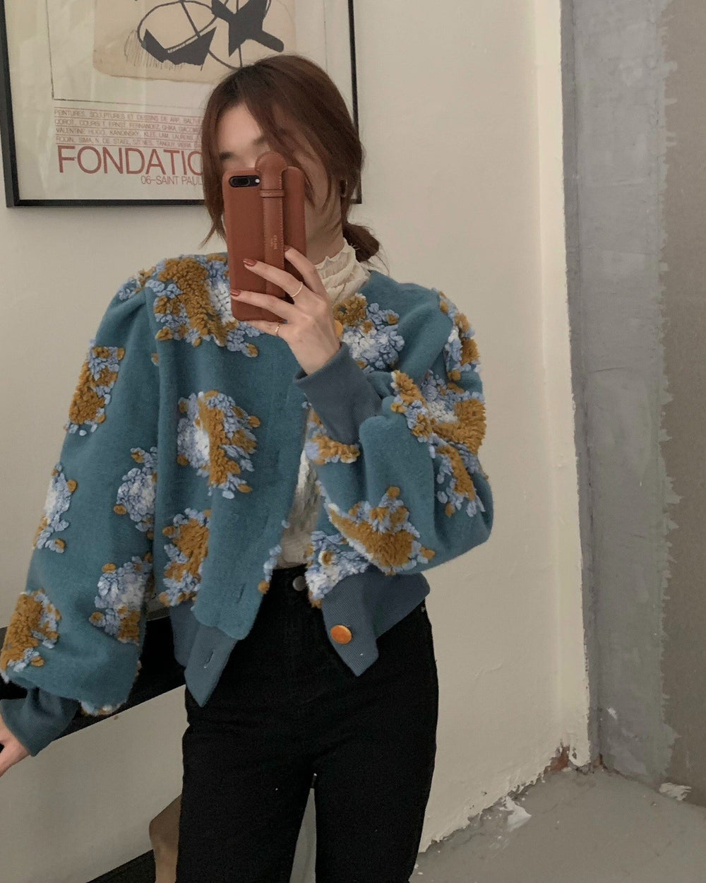 Teal flower-patch jacket with puffed sleeves and a gold button at the hem, seen from the front