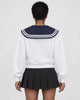Woman seen from behind in the white sweatshirt with the large navy sailor collar over a black pleated skirt