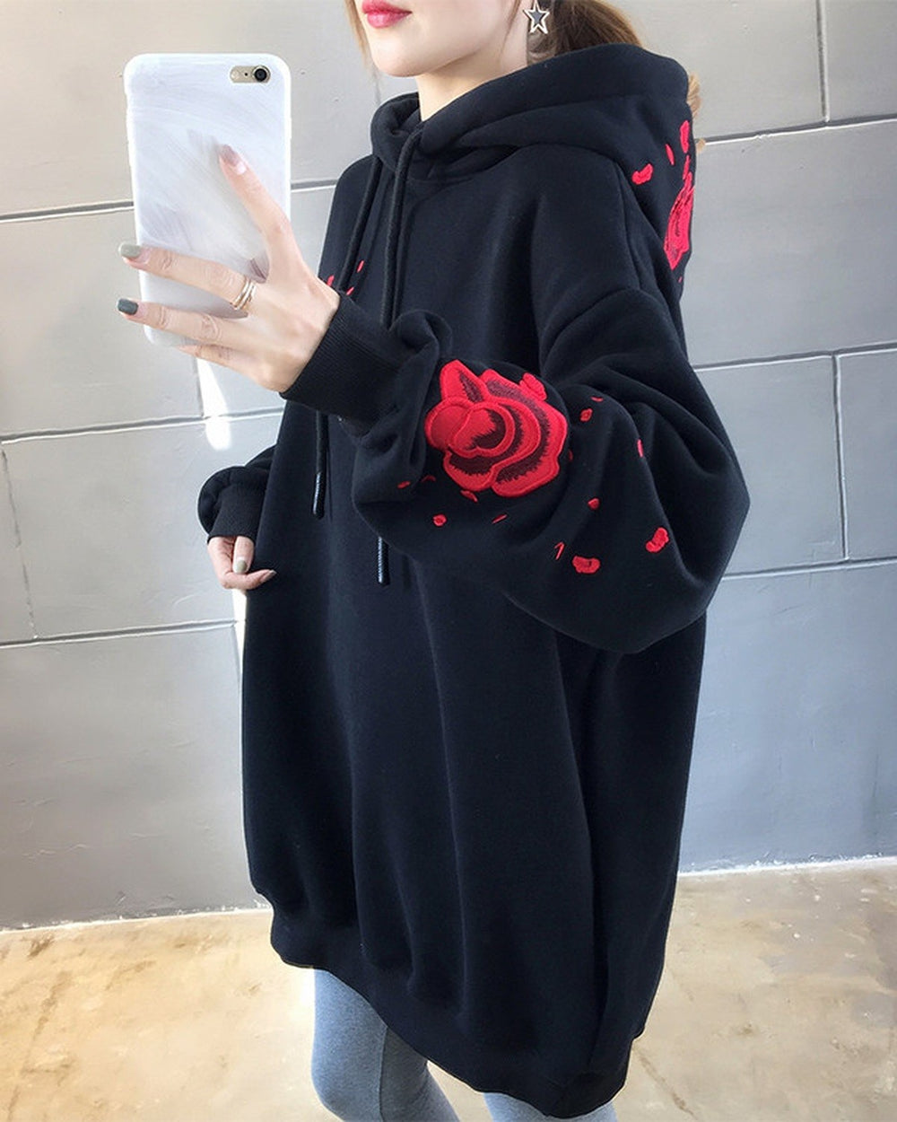 Close-up of the embroidered red rose and petals on a black hoodie sleeve