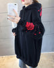 Close-up of the embroidered red rose and petals on a black hoodie sleeve