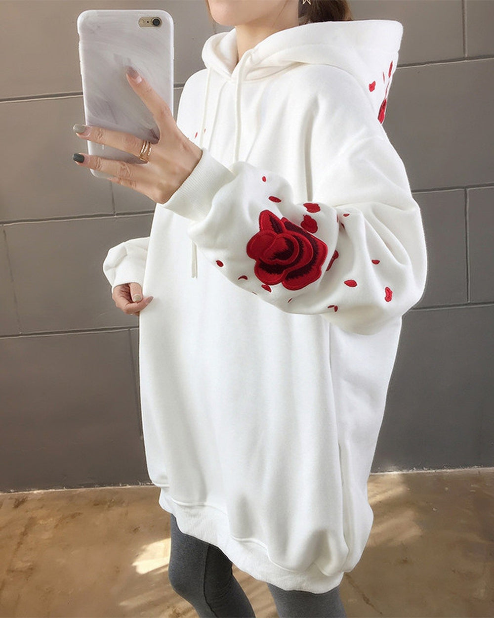 Close-up of the embroidered red rose and petals on a white hoodie sleeve