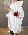 Close-up of the embroidered red rose and petals on a white hoodie sleeve