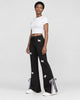Woman in black flared sweatpants with white bows, turned slightly, with a tied gingham ribbon at the hem