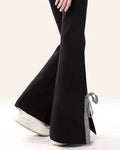 Side view of black flared sweatpants with a white bow on the leg and a gingham bow at the hem