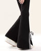 Side view of black flared sweatpants with a white bow on the leg and a gingham bow at the hem