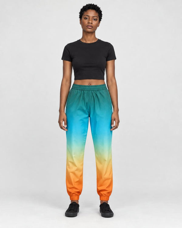 Woman in teal to orange gradient jogger pants with a black cropped tee and black sneakers, full length