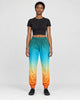 Woman in teal to orange gradient jogger pants with a black cropped tee and black sneakers, full length