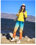 Woman walking in a yellow top and the teal to orange gradient jogger pants, three-quarter view