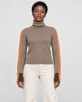 Woman standing in the herringbone turtleneck with orange sleeve stripes and cream trousers, front view
