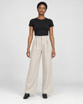 Model wearing the beige high-rise pleated wide-leg pants with a black tee and black boots, front view