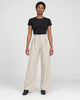 Model wearing the beige high-rise pleated wide-leg pants with a black tee and black boots, front view
